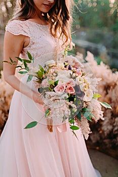 A bride holds rustic wedding bouquet consisting of different flowers. Decoration Artwork