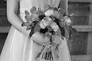 The bride holds a wedding bouquet. Black and white.