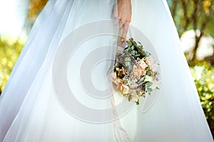 The bride holds a wedding bouquet in her hands, wedding day flowers