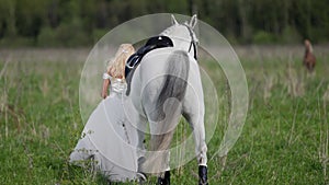 bride and horse at nature, romantic shot of young woman in wedding dress and graceful white equine
