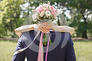 The bride hugs the groom, covering a wedding bouquet of flowers from white and red roses