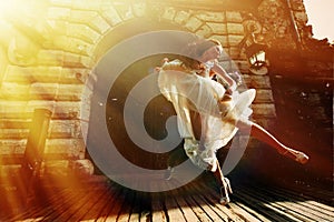 Bride jumps up in the air before an old castle in the sunrays