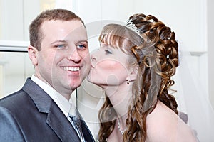 Bride kissing groom in cheek