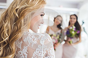 Bride in lace dress and bridesmaids with flowers in wedding