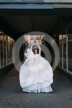 Bride lifting her hands up dancing. dress develops