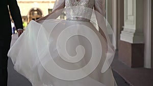 Bride in a long white wedding dress is whirling about, blowing gown in the wind.