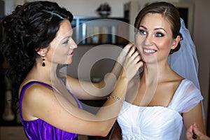 Bride looks funny while bridesmaid adjusts an earring