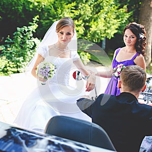 Bride looks funny while bridesmaid adjusts an earring