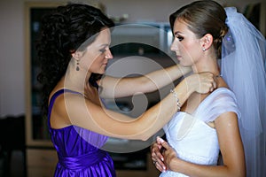 Bride looks funny while bridesmaid adjusts an earring