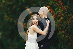 Bride looks funny with eyes open wide while she hugs a groom