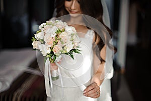 Bride morning preparation. Beautiful bride dressed in a white dress and veil with a wedding bouquet