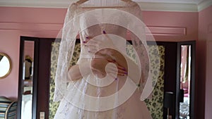 Bride morning preparation. Beautiful bride in white wedding negligee holding and hugging wedding dress. Tender moment of