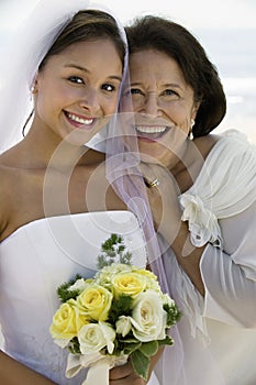 Bride and mother with flowers smiling (close-up) (portrait)