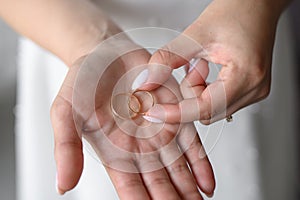 Bride with a neat manicure holds two wedding rings on her palm, close-up. Concept of love, family, wedding ceremony.