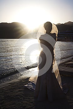 Bride on ocean or sea at sunset on wedding day photo