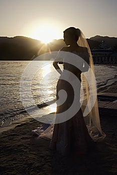 Bride on ocean or sea at sunset on wedding day photo