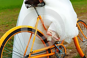 Bride on orange bike in beautiful wedding dress with lace in landscape. wedding concept.