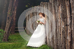 Bride in park near long wooden fence