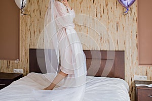 Bride in peignoir holding a wedding dress