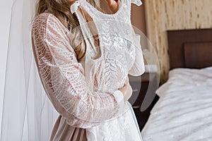 Bride in peignoir holding a wedding dress