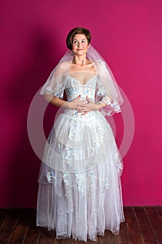 Bride on pink background. Woman dressed in wedding dress with lace, copyspace for text