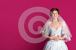 Bride on pink background. Woman dressed in wedding dress with lace, copyspace for text