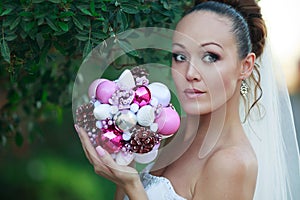 Bride portrait in white bridal veiling with artificial bunch photo session, leaves and trees background, summer weather, fashion