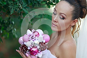 Bride portrait in white bridal veiling with artificial bunch photo session, leaves and trees background, summer weather, fashion