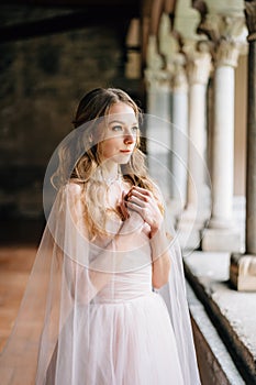 Bride prays with her arms crossed on her chest on a pillared loggia in an old villa on Lake Como.