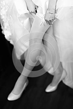 Bride puts on garters on graceful legs