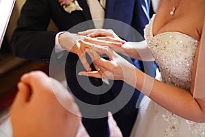Bride puts a ring on groom's finger delicately