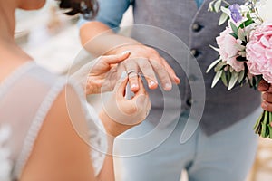 the bride puts the ring on the groom's finger during the wedding ceremony
