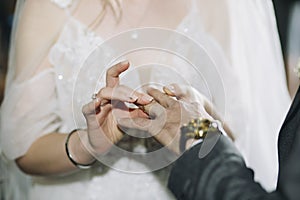 Bride puts a wedding gold ring on groom& x27;s finger in church during the wedding ceremony