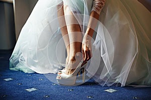 Bride puts on white shoes in preparation for the wedding