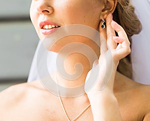 Bride putting on diamond earrings