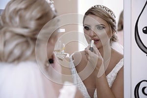 The bride putting on lipstick in living room front of mirror