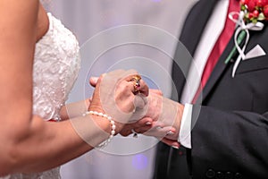 Bride putting ring on groom`s finger during wedding ceremony
