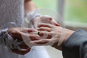 Bride putting the wedding ring on groom finger close up