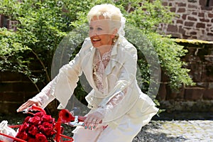 Bride radiant with joy in a romantic designer bridal suit with the red bicycle on the way to the wedding ceremony photo