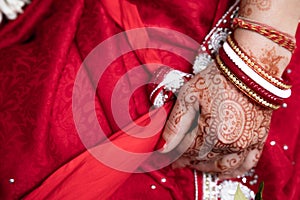 Bride in a red Sari. Beautiful traditional Indian wedding ceremony. bride`s hand is decorated with mehendi and bracelets