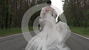 The bride runs along the road and her dress develops
