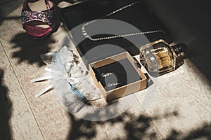 Bride`s accessories: shoes, earrings, jewelry, perfume and garter on wooden background. Wedding day concept.