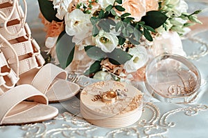 Bride`s bouquet, beige shoes, wedding rings and perfume. The bride`s accessories