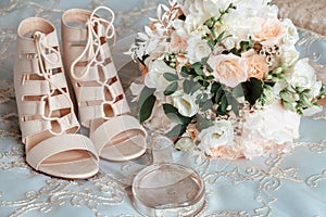 Bride`s bouquet, beige shoes, wedding rings and perfume. The bride`s accessories