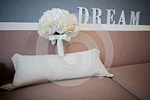The bride`s bouquet on a couch. Dream text in the background.