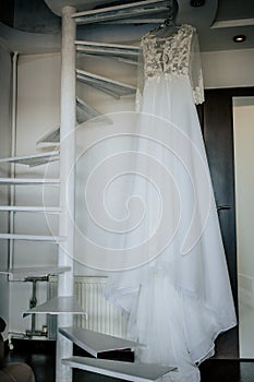 Bride`s dress on hanger on the stairs in the bride room. Wedding day