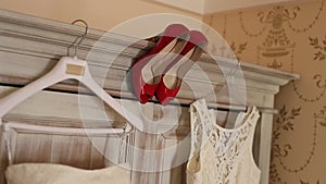 The bride`s dress hangs on the hanger on the closet and the red
