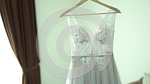 The bride`s dress hangs in the hotel room during the preparation for the wedding ceremony