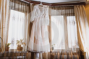 The bride`s dress hangs on the window