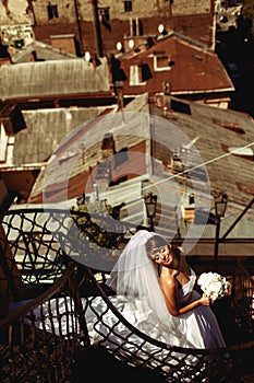 Bride`s dress lies on the spiral stairs while she enjoys sunshin